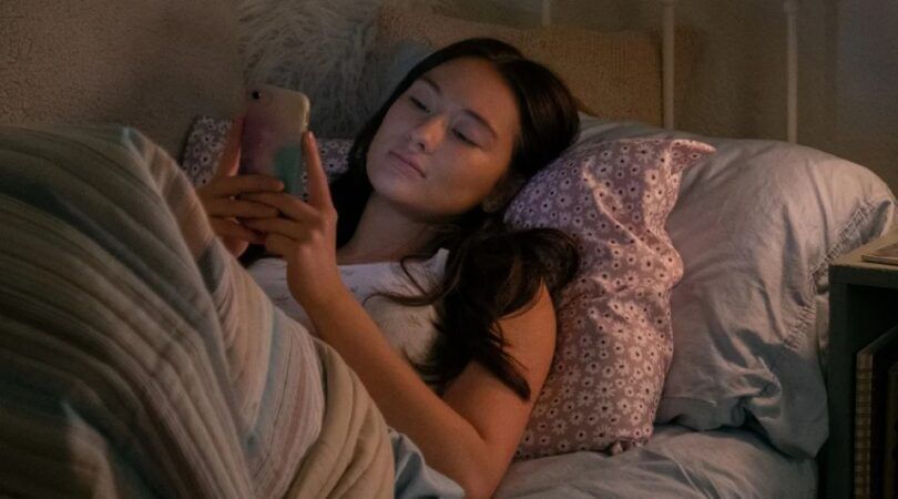 meisje ligt in bed op haar telefoon