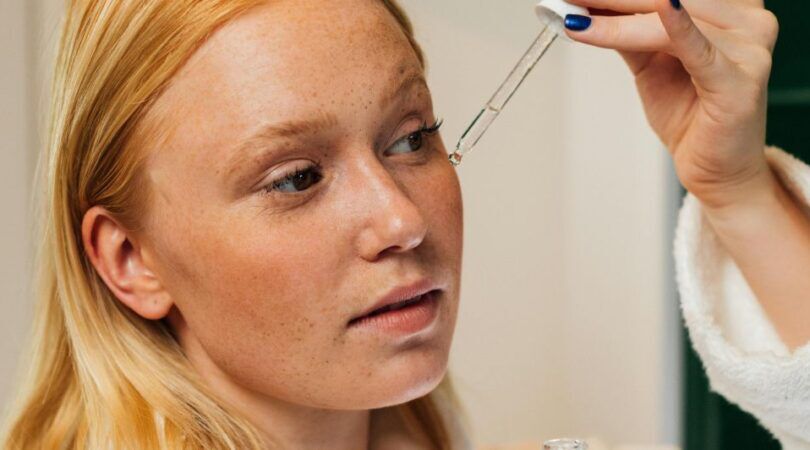 Een vrouw die serum op haar gezicht aanbrengt.