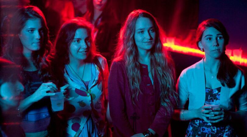 Vier meiden die in neon-lichten op een feestje staan.