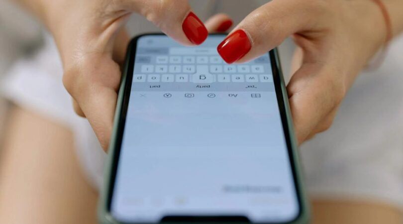 Een hand met rode nagels typt in de Notes app.