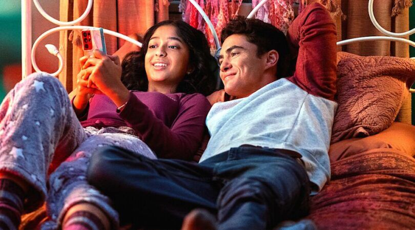 Sc&egrave;ne uit Never Have I Ever waarin Devi en Paxton op bed liggen en naar Devi haar telefoon kijken.