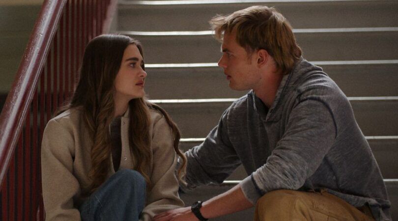 Twee personages uit de serie zitten samen op de trap.