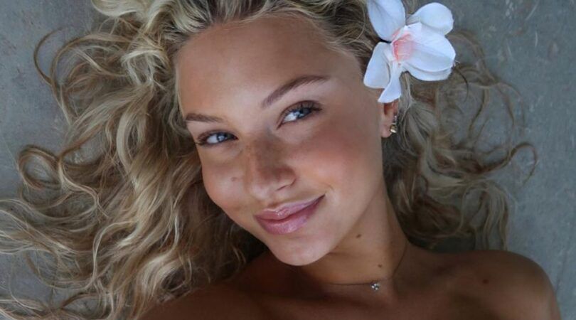 Meisje met een stralende huid en een bloem in haar haar.