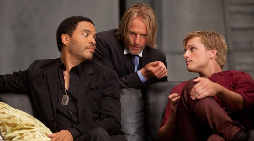 Haymitch, Peeta en Cinna zijn druk in overleg.