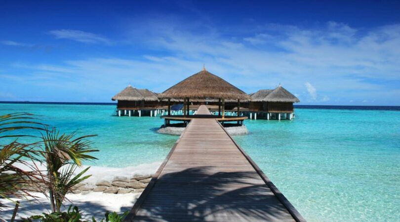 Houten vakantiehuisje op zee met een blauwe lucht.