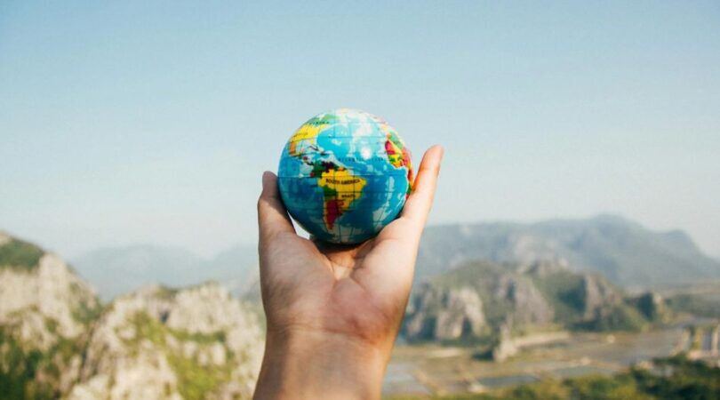 Een hand houdt een mini-wereldbol vast.