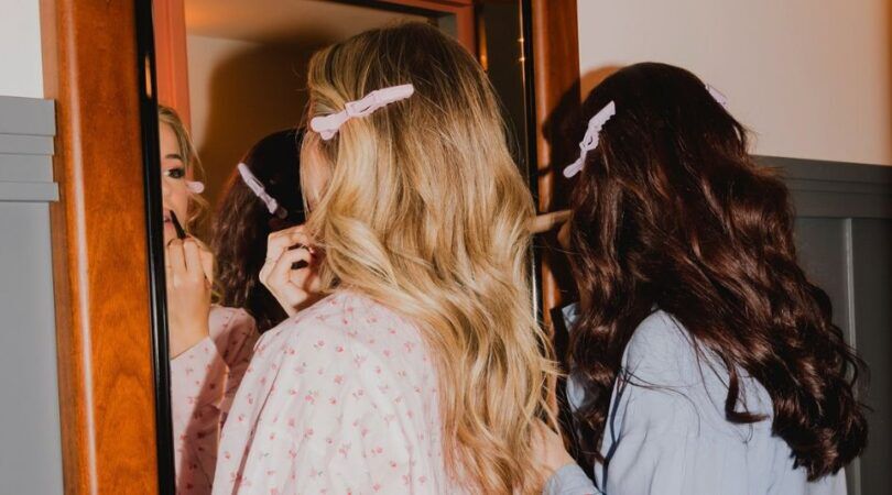 Twee vrouwen doen voor de spiegel hun make-up.