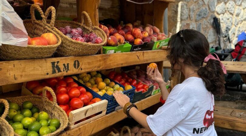 Een meisje die bij een fruitmarkt fruit uitkiest.