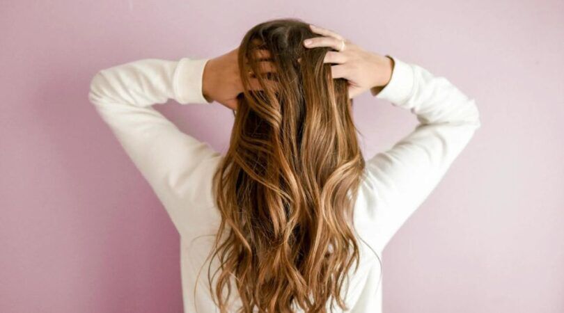 Vrouw gaat door haar haar met haar handen.