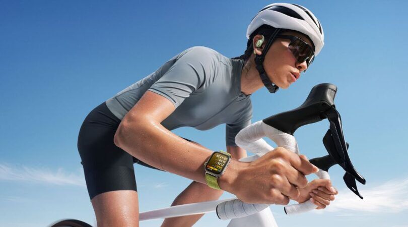 Een jonge vrouw fietst, terwijl haar horloge haar lichaamsfuncties bijhoudt.