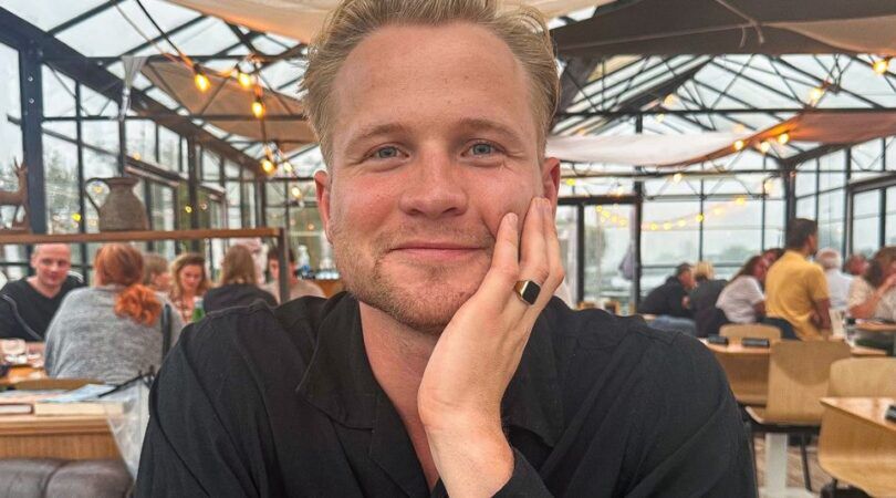 Man kijkt glimlachend in de camera.