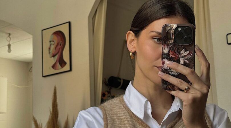 Een vrouw die een spiegelselfie maakt en naked nails heeft.