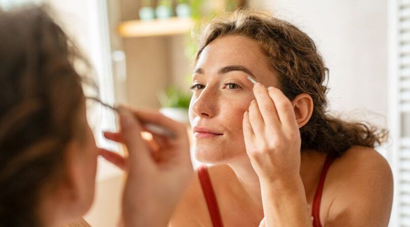 Een vrouw die haar wenkbrauwen aan het epileren is.
