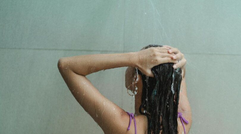Meisje wast haar haren onder de douche.