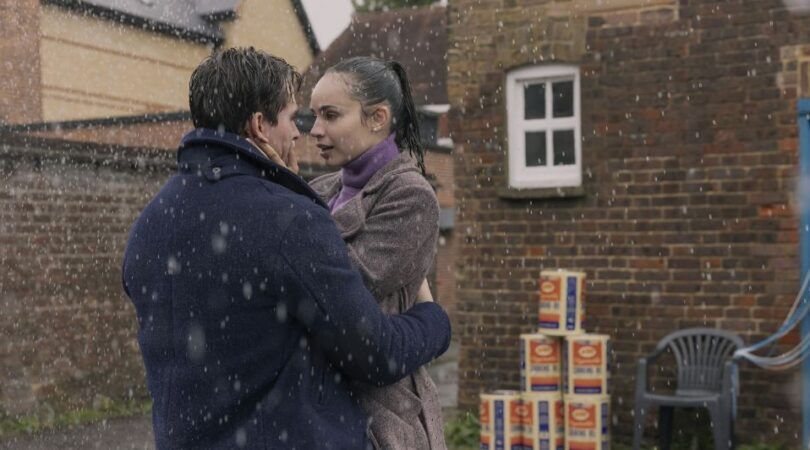 Jongen en meisje kijken elkaar verliefd aan in de regen.