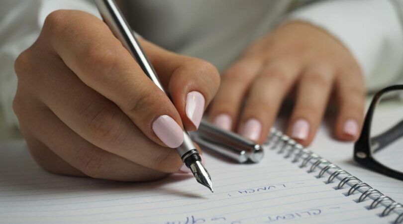 Vrouw schrijft op papier met pen.