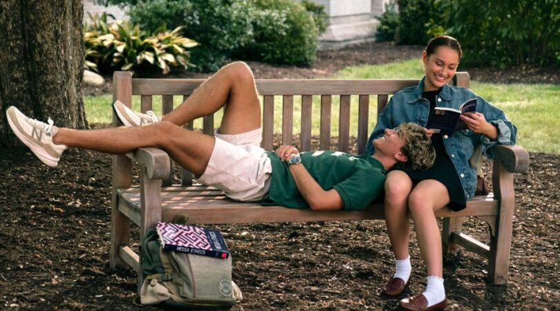 Meisje leest een boek op een bankje en een jongen ligt op haar schoot.