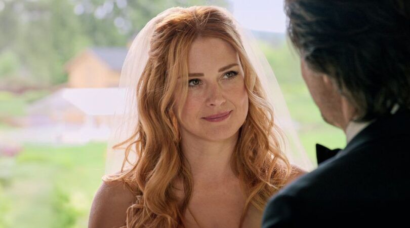 Vrouw in bruidsjurk kijkt verliefd naar man buiten beeld.