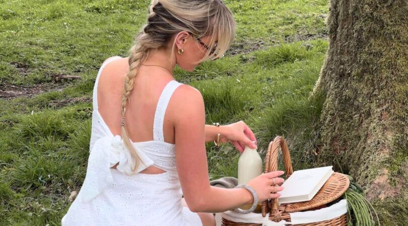 Een meisje zit te picknicken in het bos.