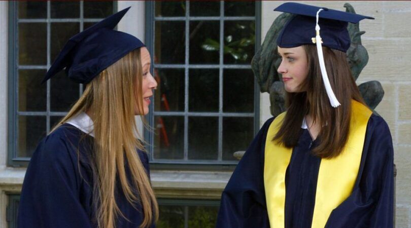 Twee vrouwen in cap and gown kijken elkaar aan.