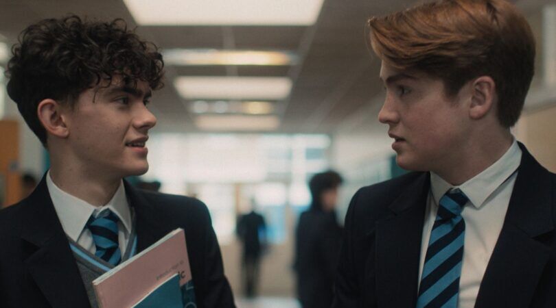 Twee jongens in schooluniform kijken elkaar aan.