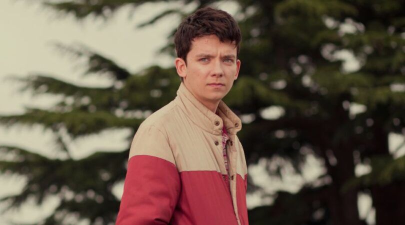 Jongen staat alleen voor bosjes en staart achter de camera.