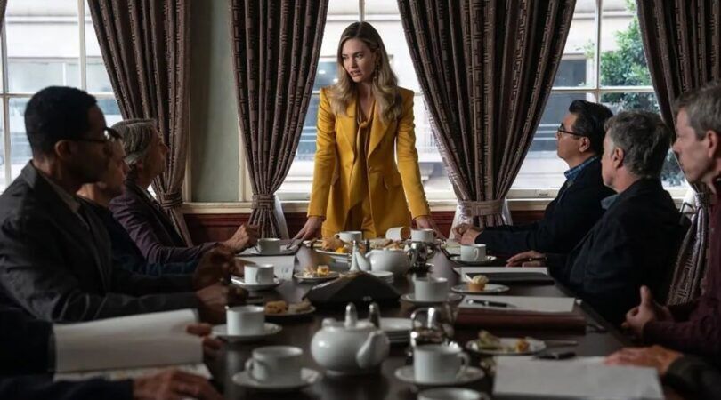 Vrouw staat aan het hoofd van een vergadertafel met mannen om haar heen.