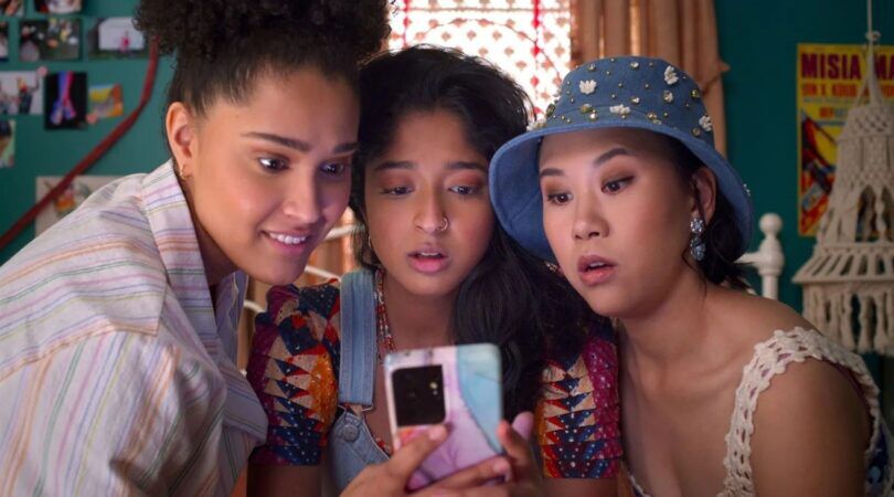 Drie meiden kijken op een telefoon.