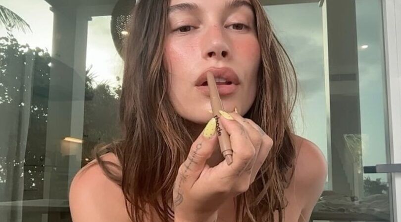 Vrouw doet een bruin-roze liptint op haar lippen.