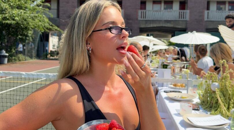 Een meisje met rouge op eet een aardbei.