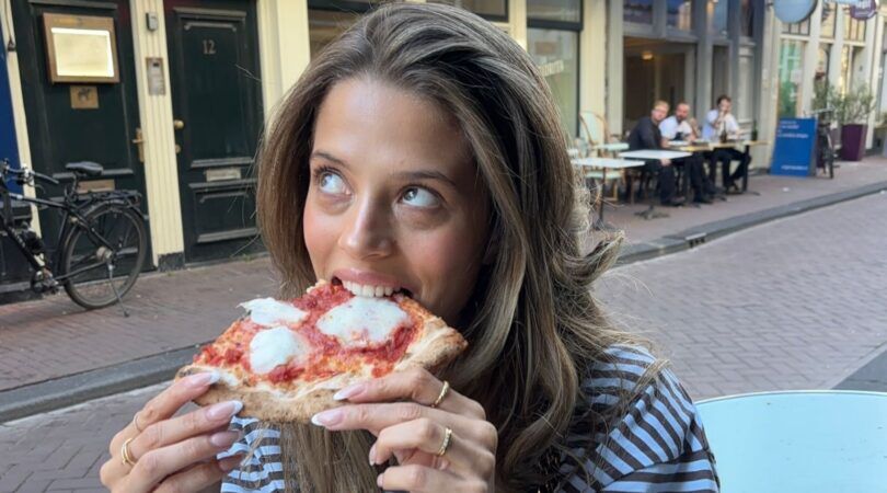 Influencer Zaar Goedemans eet een pizza op een terras.