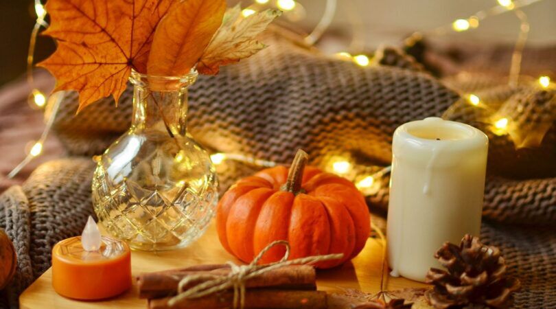 Plateau waar een pompoen, kaars en kaneelstokjes op staan.