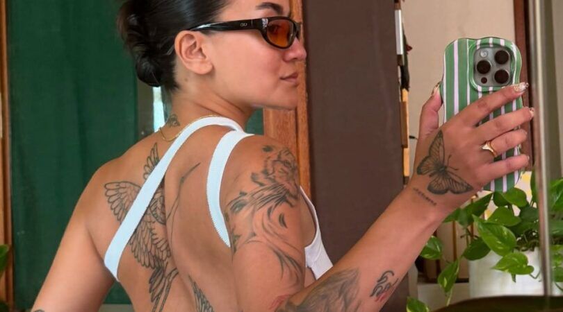 Meisje maakt een selfie in de spiegel van haar rugtattoos.