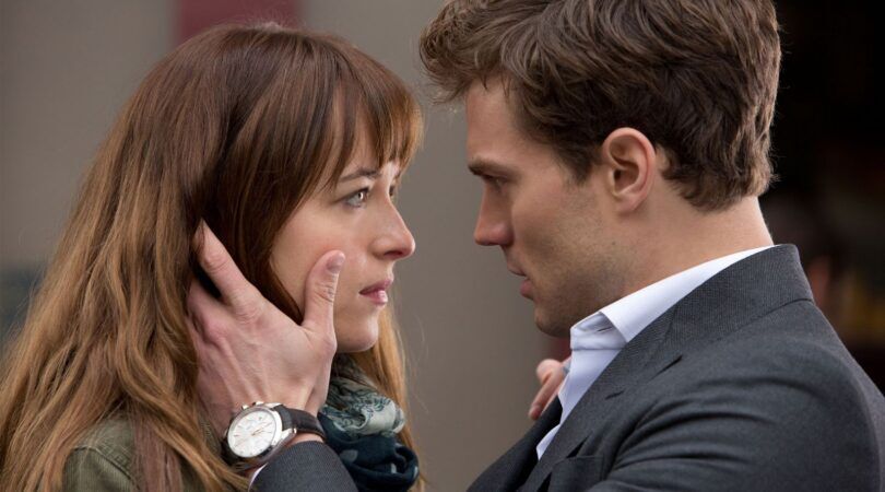 Man en vrouw kijken heel intens naar elkaar. De man houdt de vrouw haar gezicht vast. Scene uit 50 shades of grey/