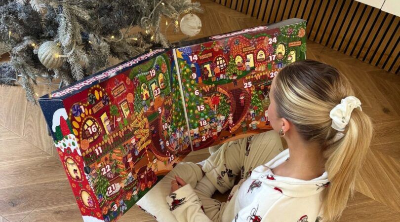 Vrouw opent adventskalender voor haar kerstboom.