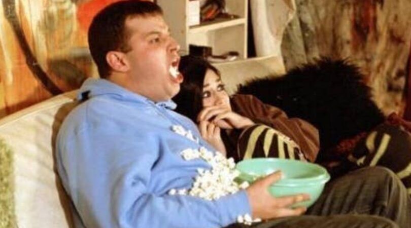 Man en vrouwen schrikken heel erg hard van een horrorfilm. Man spuugt letterlijk zijn popcorn uit. De vrouw duikt ineen.