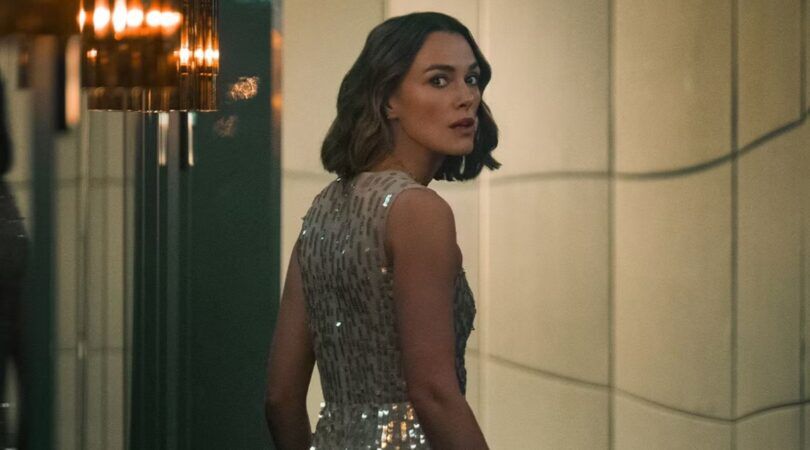 Keira Knightley, die de hoofdrol speelt in de nieuwe film: The Woman in Cabin 10, kijkt angstig over haar schouder. Ze draagt een glitterjurk.