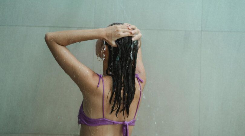 Een meisje wast haar haren in de douche.