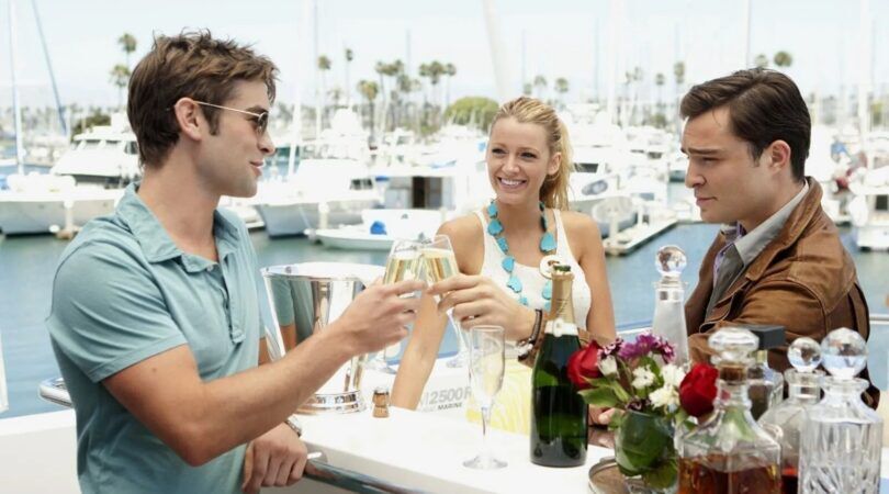 Chuck Bass en Nate Archibald uit Gossip Girl Proosten terwijl Serena van der Woodsen lachend toe kijkt.