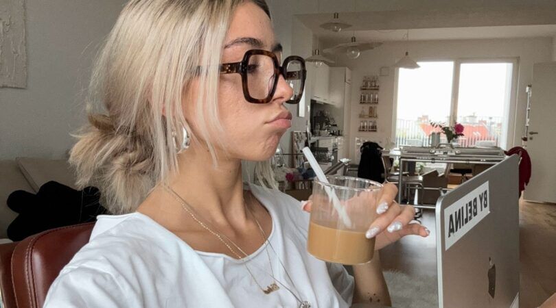 Meisje zit met een ijskoffie achter haar laptop.