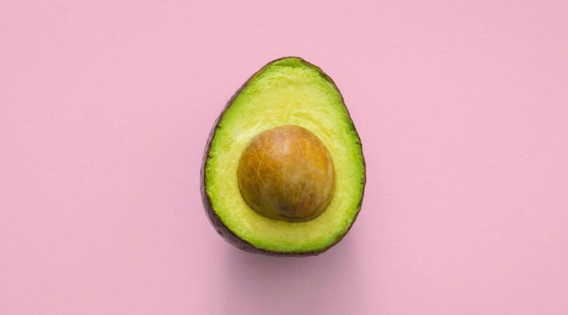 Een avocado met een roze achtergrond.