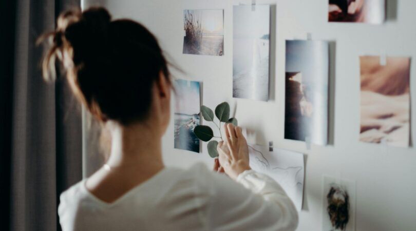 Een vrouw hangt foto's op in haar kamer.