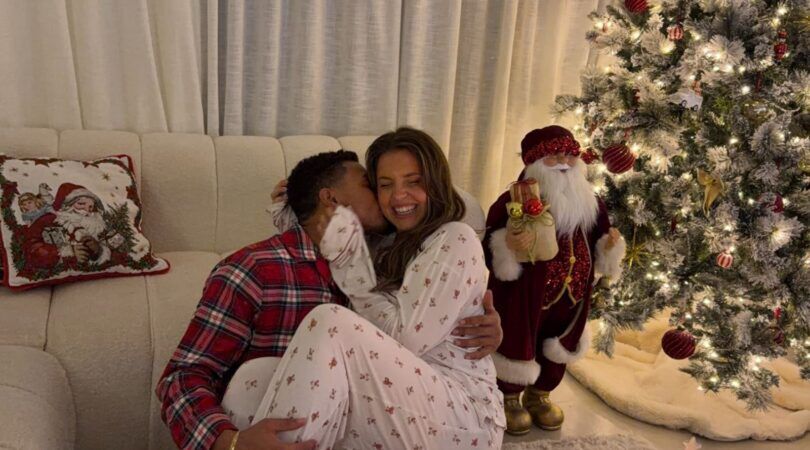 Man en vrouw knuffelen samen voor de kerstboom.