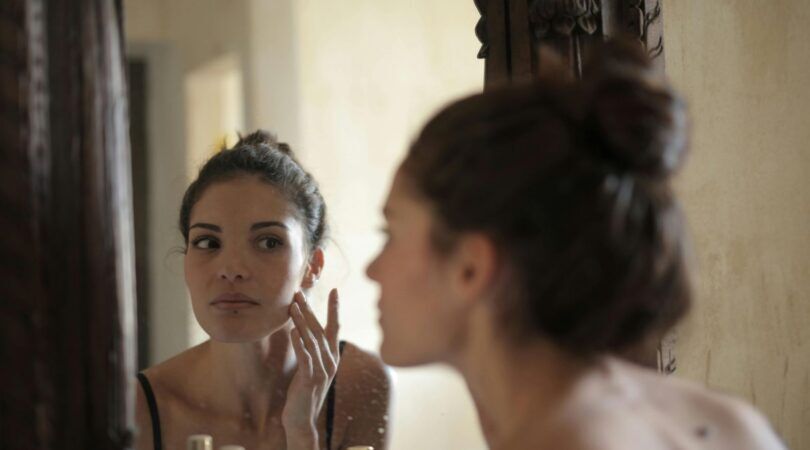 Vrouw kijkt naar haarzelf in de spiegel