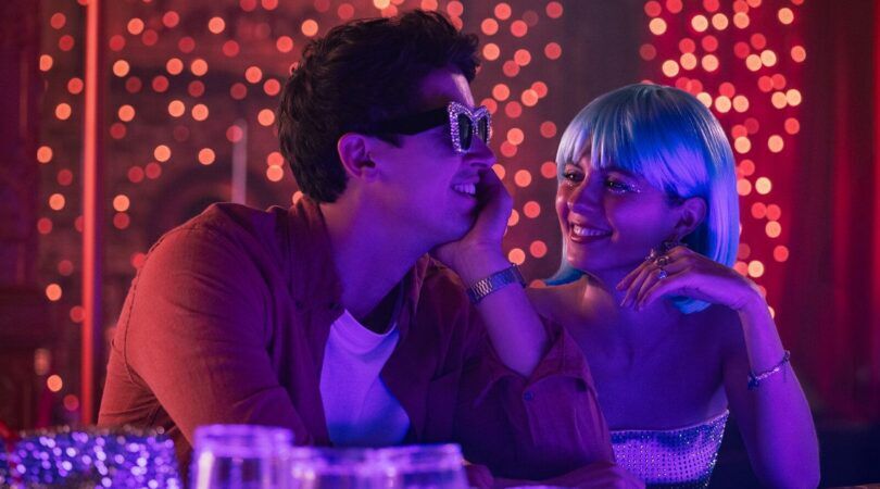 Een jongen met een zonnebril en een meisje met een pruik in een caf&eacute;.