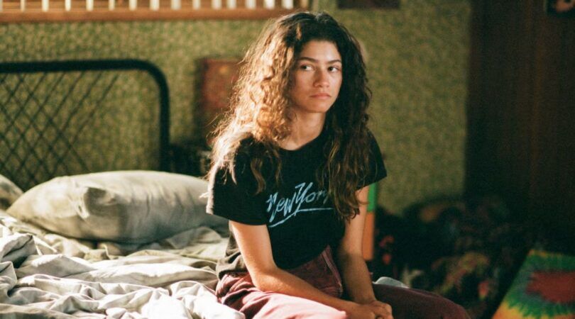 Rue van Euphoria zit op haar bed.