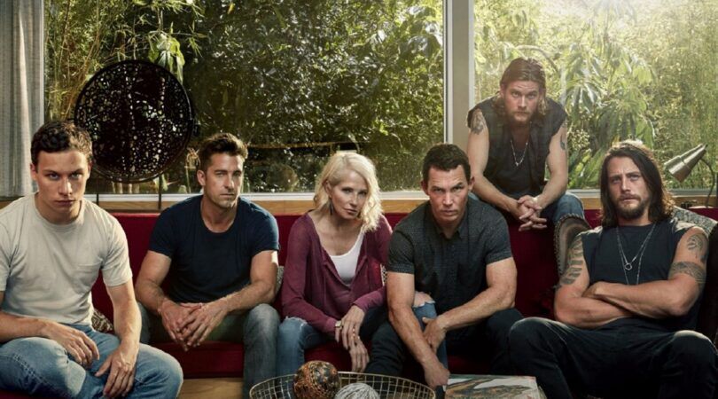 Sc&egrave;ne uit de serie Animal Kingdom. De familieleden zitten op een bank en kijken intens voor zich uit.