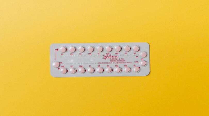 Anticonceptie pil met gele achtergrond.