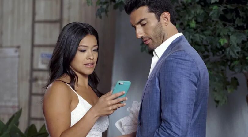 Jane kijkt op haar telefoon terwijl Raphael naast haar staat.