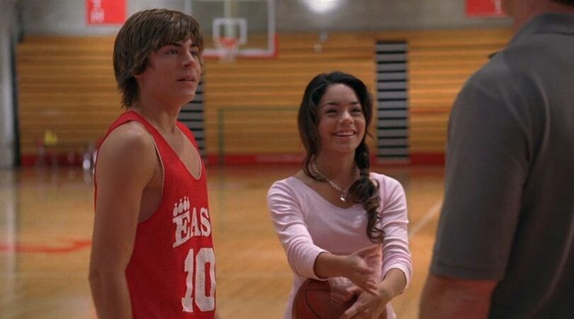 Gabriella die naast Troy met een basketbal in haar handen staat.